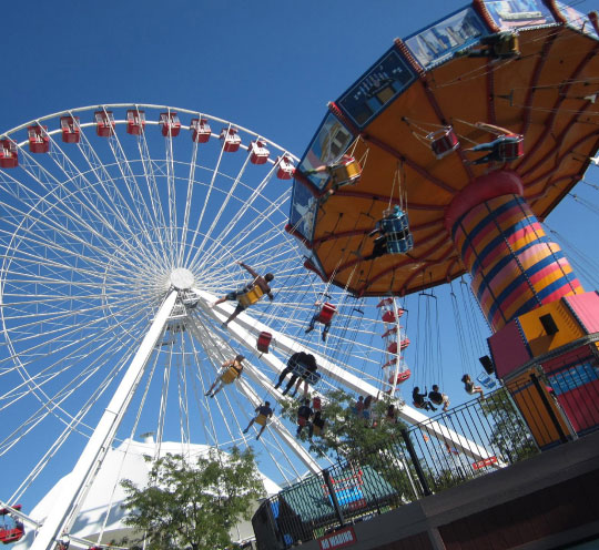A Ferris Wheel and brightly colored carnival swing ride. 
