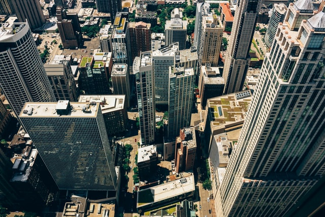 Birds eye view of tall buildings at midday with long shadows on the streets