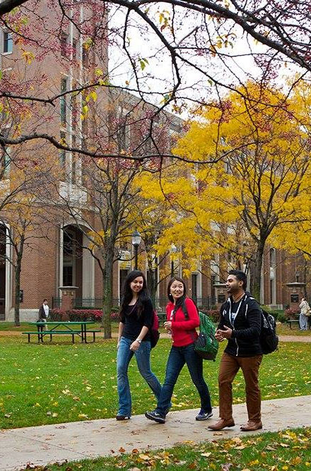 Three friends walk on campus in autumn.