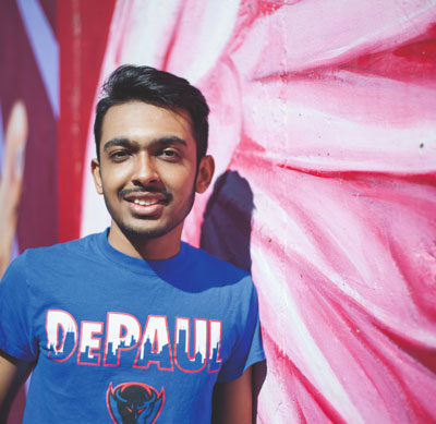 A smiling young man leaning against a wall mural 