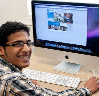 A smiling young man works in a computer lab