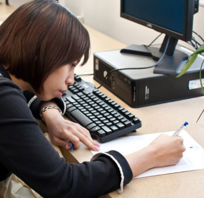 A young woman in class writing on a paper